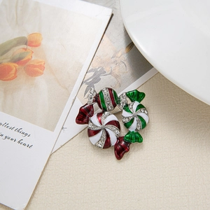 Christmas candy cane brooch with red white green enamel and rhinestones on beige fabric