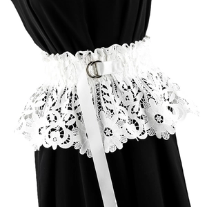 Detail of white floral lace corset belt with silver double ring buckle on black fabric