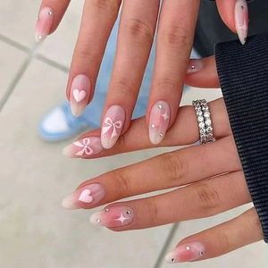 Almond shaped almond press-on nails with pink heart, bow accents and rhinestone gradient