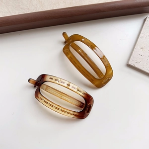 Macro shot of oval amber and tortoiseshell hair clips with hollow minimalist design