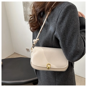 Detailansicht einer cremefarbenen Ledertasche mit goldenem halbrundem Verschluss