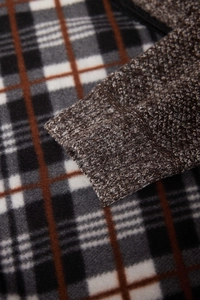 Macro view of brown chunky knit cuff with a plaid fleece lining detail on the jacket