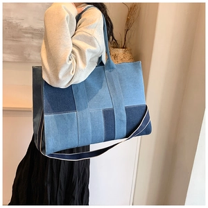 Detail view of large denim patchwork tote bag with stylish wide shoulder strap on model