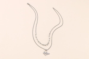 Detail of layered silver necklace featuring a paperclip chain and hollow butterfly pendant