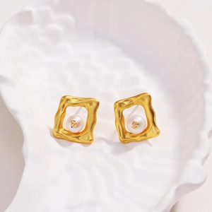 Détail de boucle d'oreille carrée ajourée plaquée or 18k avec perle sur plateau