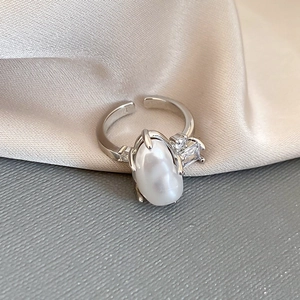 Macro detail of adjustable silver ring with baroque pearl and step-cut side stones