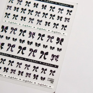 Detail of thin nail art stickers featuring black bowknots and pink polka dots pattern