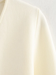Detaillierte Nahaufnahme der Stricktextur und V-Ausschnitt-Naht der cremefarbenen Strickjacke