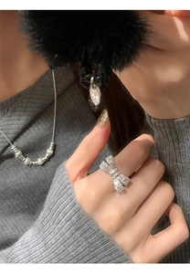 Macro shot of a silver bow ring with shimmering cubic zirconia on a female model finger