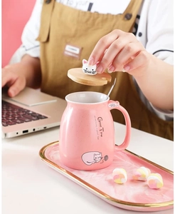Detail einer rosa Keramiktasse mit Holzdeckel, die auf einem Schreibtisch geöffnet wird
