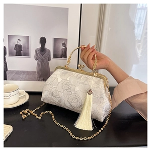 Detail of white silk evening shell bag with floral embroidery, tassel and gold chain