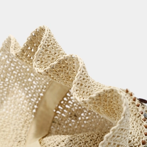 Détail d'un chapeau de paille tissé main montrant la texture et le bord ondulé