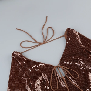 Close-up of bronze sequin fabric and tie-up halter straps on a slim fit dress