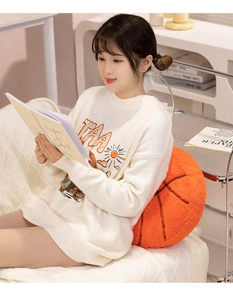 Cozy basketball plush pillow used as a back support on a white sofa in a home setting