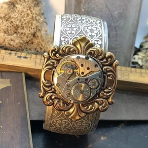 Detail of vintage steampunk wide cuff bracelet featuring mechanical gears and heart patterns
