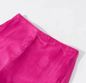 Detail of rose pink pleated fabric with a waist tie and glossy velvet texture on a dress