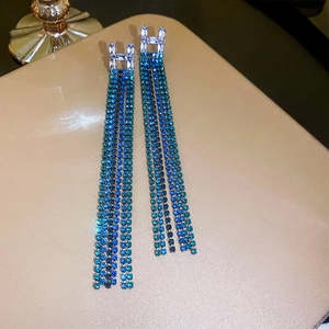 Close-up of silver H-letter earrings with gradient blue crystal fringe tassels