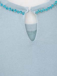 Detail of light blue knitted sweater featuring keyhole neckline with blue rhinestone trim