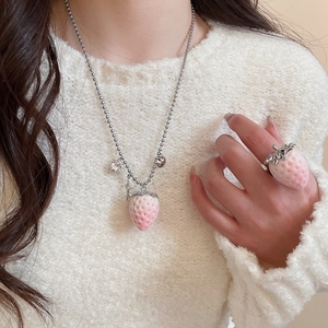Detail of pink strawberry pendant necklace and matching silver ring on a model