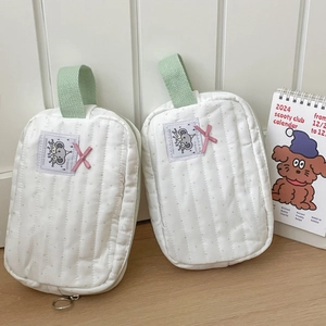 Detail of white quilted elephant pouches with mint green handles and ribbon accents