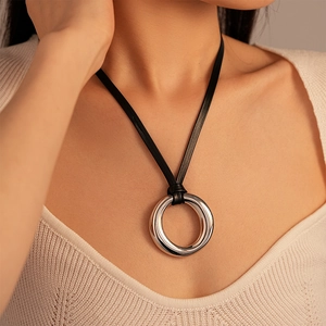 Dettaglio di un grande ciondolo ad anello in metallo argento su un cordoncino di cuoio nero