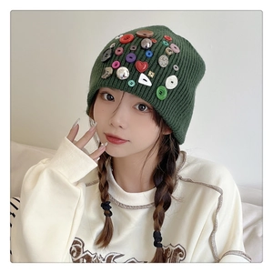 Close-up of dark green knit beanie with colorful decorative buttons and detailed texture