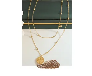 Detail of 18k gold layered necklace featuring a round evil eye pendant and beaded chain