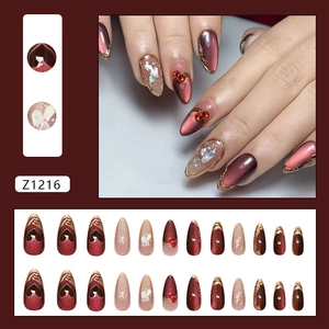 Deep red cat eye press-on nails set with gold gilding and pearl accents in long stiletto shape