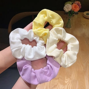 Detailed view of colorful ribbed fabric hair ties in white, yellow, and purple colors
