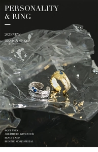 Detail of irregular lava texture ring in gold and silver finish with blue zircon