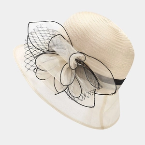Detailed texture of cream organza bow and black mesh on a straw sun hat
