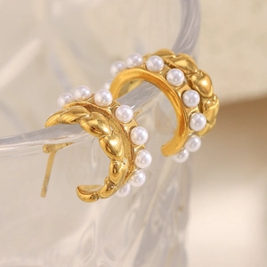 Detail of gold C-shaped earrings with white pearl edge and twisted rope texture design