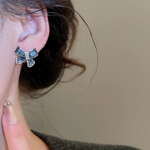 Macro view of black enamel bow stud earrings with gold edges and inlaid crystals