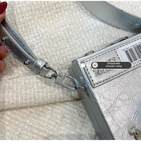 Détail du sac caméra argenté à texture vintage avec bandoulière amovible et crochet
