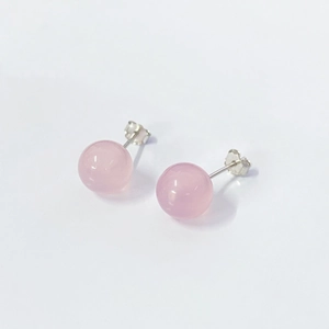 Macro shot of polished spherical pink crystal studs with s925 silver needles on white background