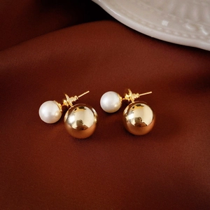 Macro shot of double-sided earring featuring a white faux pearl and golden metal ball