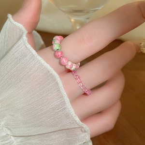 Detail view of pink beaded rings with floral textures and faceted crystals on model