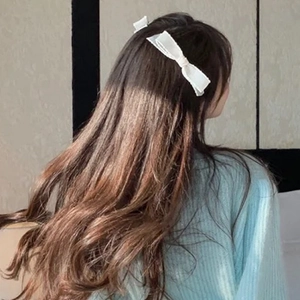 Elegant white fabric bow hair clip worn by a model to style a half-up hairstyle