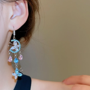 Detailed close-up of long tassel earrings with blue and pink crystals on a model