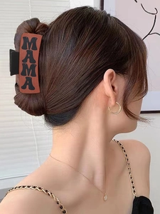 Side view of a brown hair claw clip with MAMA lettering worn by a model