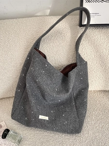 Dark grey felt tote bag with white star pattern on a cozy sofa background
