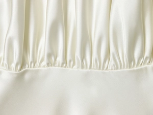 Macro shot of draped cream satin fabric showing smooth texture and gathered details