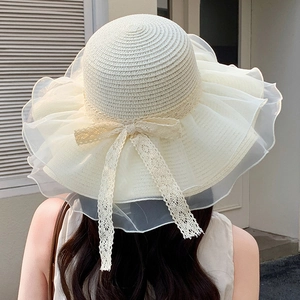 Detail of elegant summer straw sun hat featuring organza ruffled brim and lace bow tie