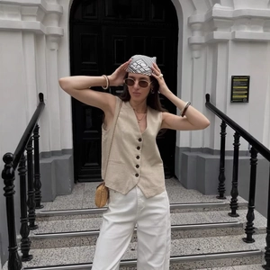 Women's chic beige V-neck buttoned vest paired with casual white trousers in street style
