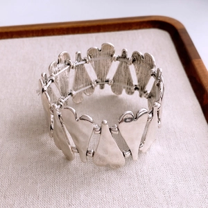 Close-up of heart-shaped metal link elastic bracelet with textured vintage silver finish
