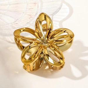 Close-up of golden metal hollow flower hair claw clip with polished finish details