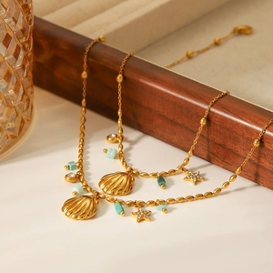 Detail of gold double-layered shell and starfish necklace draped on a wooden tray