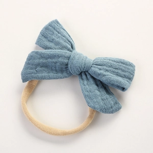Gros plan d'un bandeau bébé en mousseline de coton bleu avec élastique sur fond blanc