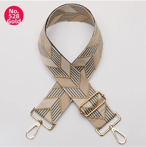 Detail of adjustable woven bag strap with geometric wave pattern and gold metal buckles
