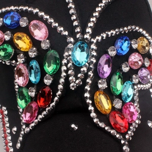 Macro shot of colorful rhinestone butterfly embellishments on black denim cap